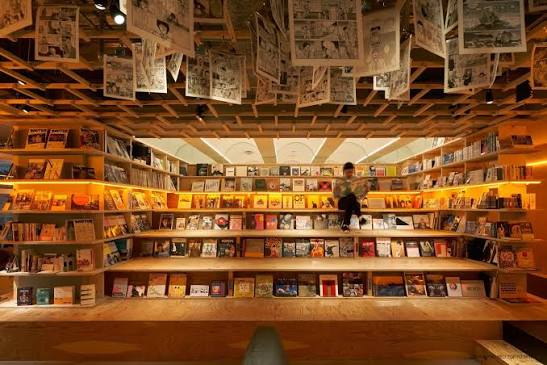 Sleeping berth cut into a wall of book shelves behind a curtain
